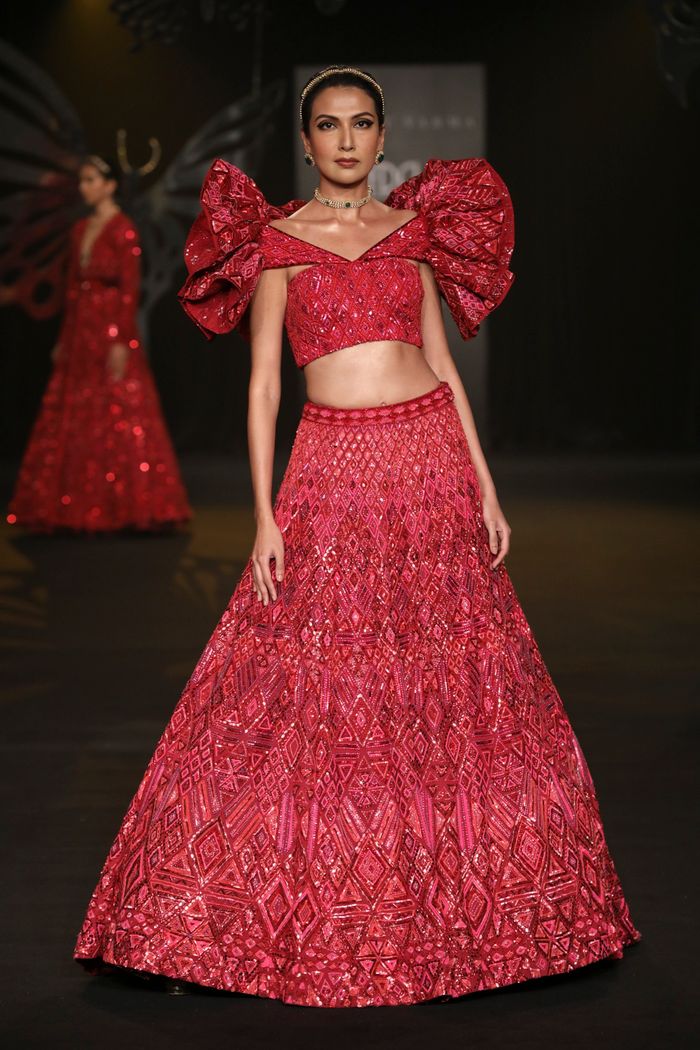 Model showcasing a red embroidered outfit at a New Delhi fashion show.
