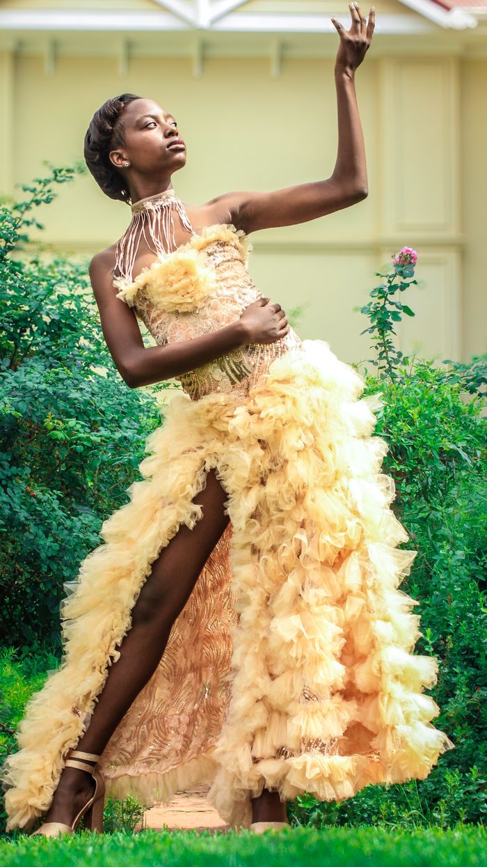 Elegant portrait of a woman in a luxurious feathered gown posing gracefully in a vibrant garden.