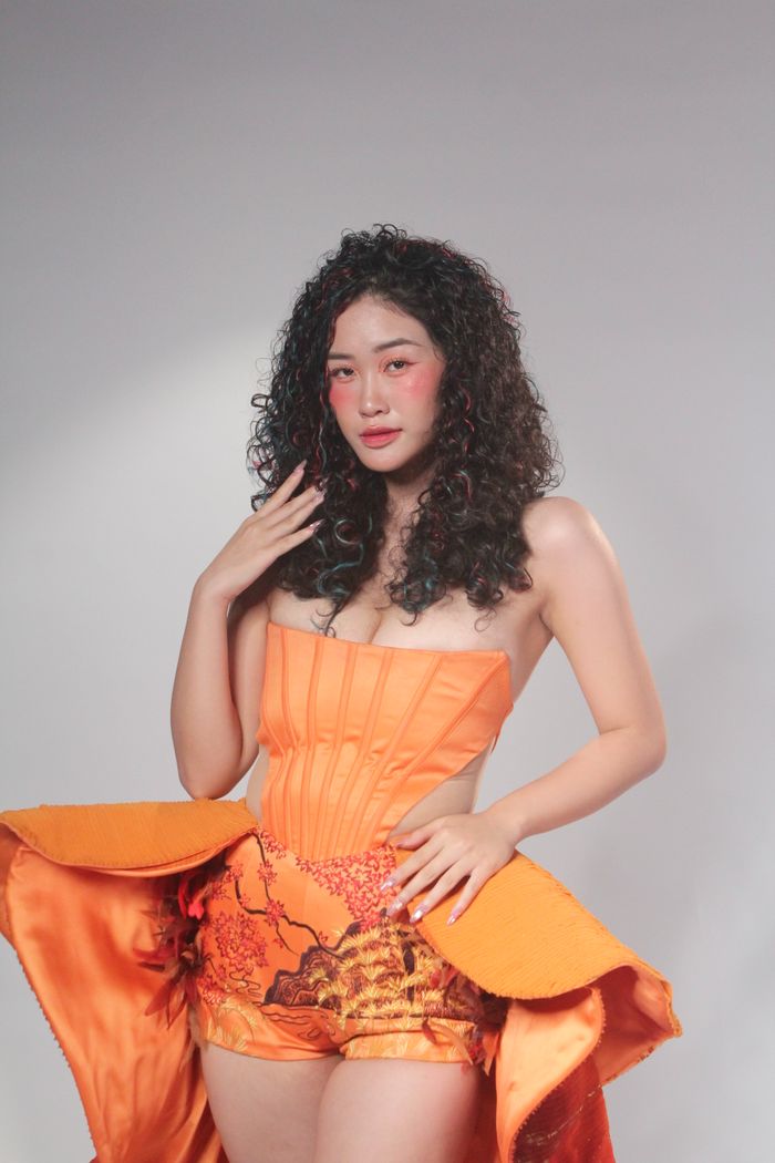 Model posing in an eye-catching orange outfit against a neutral background.
